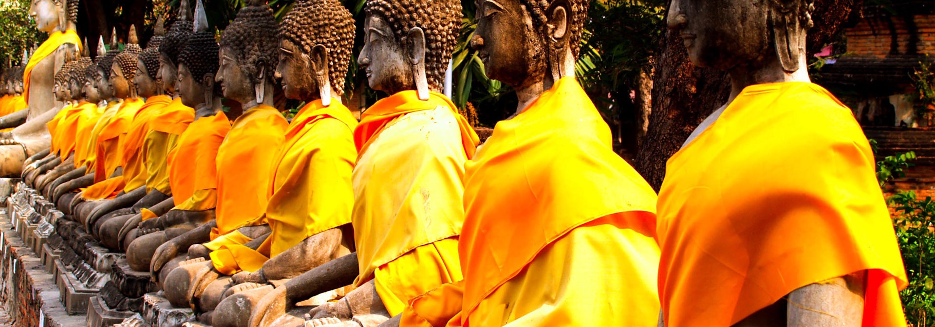 Thailandske stenfigurer af munke med gule koftedragte