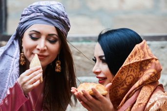 Azerbaijan Two Women Celebrating Novruz Dressed In Traditional Azerbaijani Clothes With National Pastry Baklava And Shekerbura Horizontal