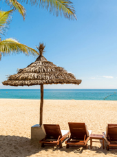 Udsigt over vandet med tre lænestole og stråparasol på Hoi An i Vietnam