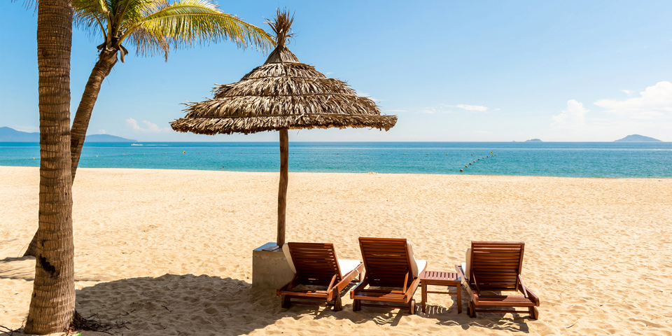 Udsigt over vandet med tre lænestole og stråparasol på Hoi An i Vietnam