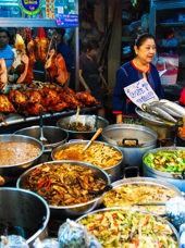 Kvinde der sælger mad på madmarked i Bangkok