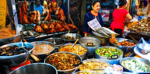Kvinde der sælger mad på madmarked i Bangkok