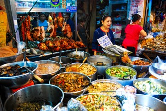 Kvinde der sælger mad på madmarked i Bangkok