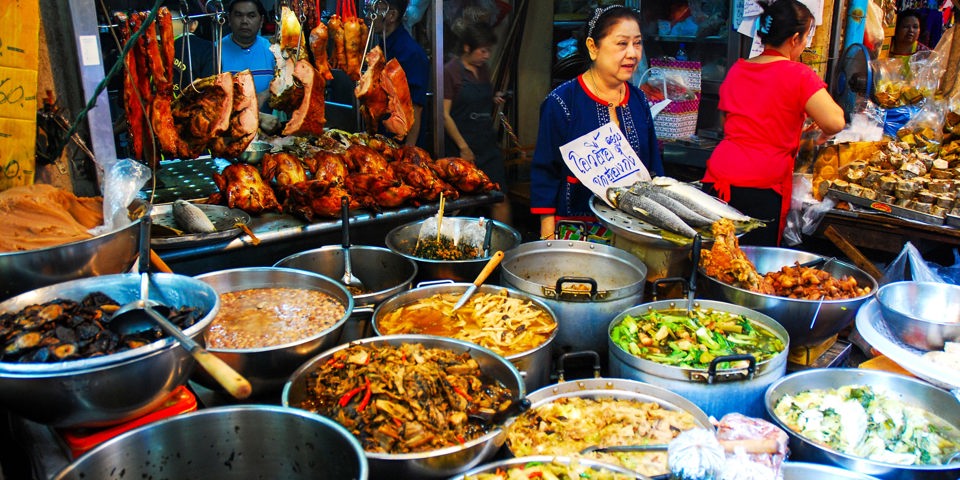 Kvinde der sælger mad på madmarked i Bangkok